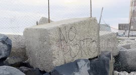 The protest sign 'no porto' on a large concrete block at the entrance to the old lighthouse in the area where Royal Caribbean plans to build the first large privately managed tourist port in Italy in Fiumicino, near Rome.