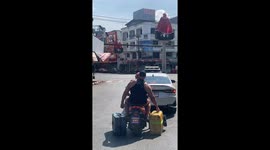 Tourist carries suitcases in either hand while riding pillion on motorcycle