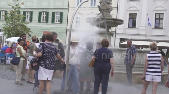 People are refreshing with water mist in the middle of the city in Bratislava during hot summer day.