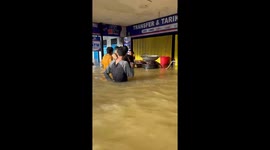 Hungry locals brave chest-deep flood to buy street food from stall