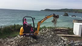 Girl builder in pink learning to drive a digger... On a cliff top! 