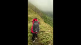 Hiker battles through howling winds on hillside