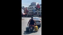 Tourist carries suitcases in either hand while riding pillion on motorcycle