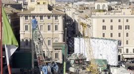 Detail of the cars passing through the first stretch of Via del Corso and in the foreground the construction site of the new Metro C station in Piazza Venezia and the Italian flag in Rome.