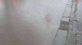 The accumulated water makes half the roadway impassable and forces pedestrians to jump onto the sidewalk on a rainy February day in a suburban area of Rome.
