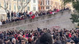 Overview of the gardens of Piazza Vittorio filled with people while Chinese children on stage sing traditional songs during the Chinese New Year celebrations in Rome.