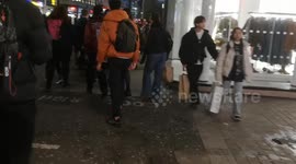 A man attempts to freak people out with a fake snake as he walks down Oxford Street