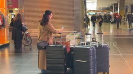 A woman with many large trolleys waiting on a day when the incoming train board shows heavy delays of up to more than 3 hours at Termini Station in Rome.