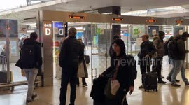 Travellers exit the platform area after arriving at the station on a day when the arrival timetable shows heavy delays of up to three hours at Termini Station in Rome.