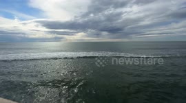Wide shot of a calm, moving sea and a sky with few clouds on a clear February day at the Lido di Ostia in Rome.