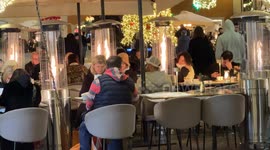 Tourists sit at tables outside a venue with heating towers to mitigate the temperature on a cold Christmas Eve in Rome.
