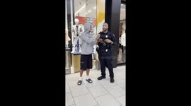 Young man interviewing cop and his pants suddenly fall down prank public experiment