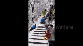 Tourists slide headfirst down several flights of stairs as heavy snow causes chaos at mountain trail in China