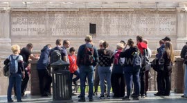 Tourists look at the Arch of Septimius Severus under the Capitoline Hill on a beautiful sunny day with spring temperatures in February in Rome.