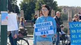 A protester holds up a sign in the colours of the Russian flag and the words 'Russians agains war' during the sit-in to demonstrate against the “Putin regime” and to promote the “Energy For Life” campaign by some Russian dissidents in Rome.