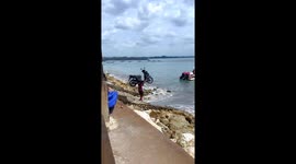 Person carries motorcycle to a boat in Sanur, Bali