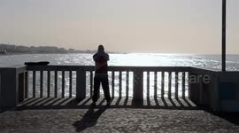 A man makes movements in the morning facing the sun and the sea on the pier at Lido di Ostia in Rome.