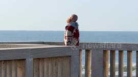 A man makes movements with his head facing the sea and under the sun on a clear morning in late February on the pier at Lido di Ostia in Rome.