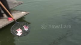Woman collects money dropped into river