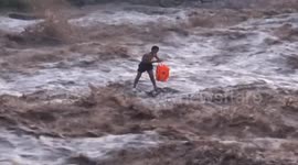 Man balances on two rocks after getting caught in fast-flowing floodwater