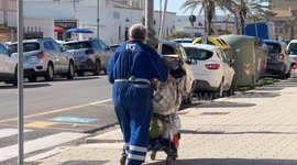 A homeless man transports his belongings with a supermarket shopping cart in a suburban area of ​​Rome.