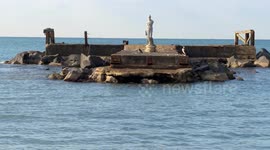 Two crows and a cormorant in front of the statue of the Venus of the Ropes on the remains of the Fishermen's Pier at the Lido of Ostia in Rome.