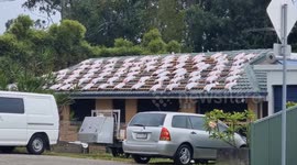 Aussie homeowner prepares for Cyclone Alfred by placing heavy sandbags on roof
