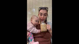 Baby's eyes light up as mum drinks iced coffee