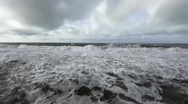 Wide shot on the rough sea and cloudy sky on the coast of Lido di Ostia in Rome.