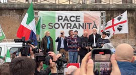A protester speaks from the stage with the words ‘peace and sovereignty’ written on it while people sell waving Italian flags during the demonstration entitled ‘Peace and sovereignty’ promoted by the leaders of Democrazia sovrana popolare Marco Rizzo and