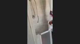 Woman comically struggles with an out-of-control high-pressure shower head