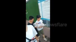 China: Two Boys Carrying Their Dog End Up Dropping It