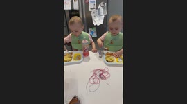 Adorable moment twin sisters make plane noises as they spoon-feed each other