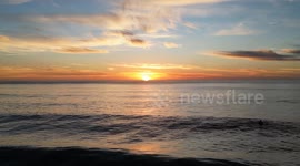 Shot of a surfer and a low altitude drone flight over ocean in Calrsbad, CA