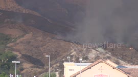 Spectators watch Fire crew hose hillside at 