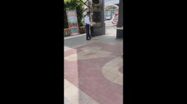 Kind security guard fans cat suffering from the heat