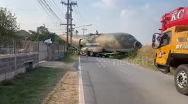 Truck carrying military plane navigates a tight corner