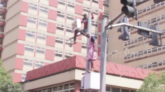 Protesters sitting atop traffic lights in Nairobi's CBD during a demonstration against the Finance Bill