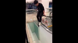 A young man falls from an escalator in a shopping center