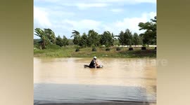 Motorist wades through flooded road in Thailand