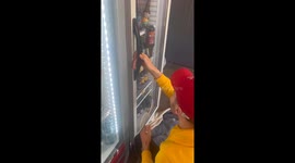 Man skilfully catches falling bottle as he opens fridge door