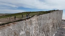 Vistors to Birling Gap, UK  walk close to the edge of the crumbling cliffs
