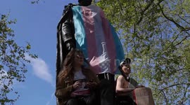 Topless trans activist scales statue of Benjamin Disraeli, UK  Prime Minister (1804 – 1881) during protest at Parliament Square London