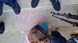 Trans activist graffitis the platform which which holds statues on Parliament Square