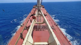 Ship's crew is removing rust by using hydro-blasting machine on crane