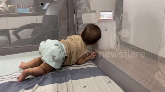 Oh! what is the baby lurking about? No!Super cute baby in lying and crawling position watching cartoons with the blinds blocked