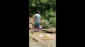 Tourist ambles through waterfall unaware of CRAB on his back