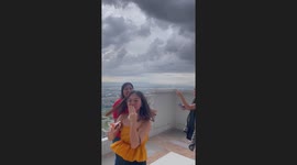 Friends giggle as hair stands up from static electricity before storm