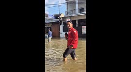 News reporter stands in knee-deep floods in Indonesia