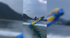 Banana boat goes airborne before flipping and tossing riders into lake